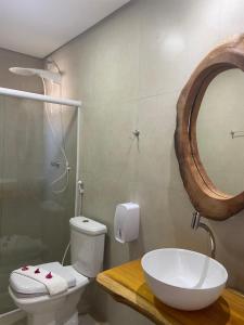 a bathroom with a sink and a toilet and a mirror at Pousada Canouan in Japaratinga