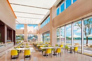 a restaurant with tables and yellow chairs and windows at Element Suzhou Science and Technology Town in Suzhou