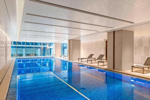 a large swimming pool with blue water in a building at Marriott Executive Apartments Hangzhou Yuhang in Hangzhou
