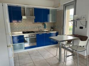 uma cozinha com armários azuis e uma mesa com cadeiras em Appartamento Pescara Sud em Pescara