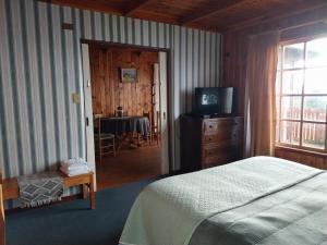 1 dormitorio con 1 cama, TV y mesa en Cabañas Los Bajos en Frutillar