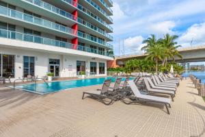 a row of chaise lounge chairs next to a swimming pool at Modern one bedroom rental at Beach Walk resort Miami 18th floor in Hallandale Beach