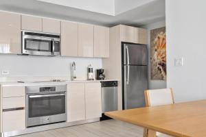 a kitchen with white cabinets and a stainless steel refrigerator at Modern 2 bed at Beach Walk 17th floor Miami in Hollywood