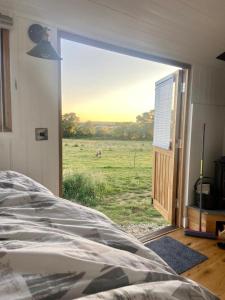 a bedroom with a view of a horse in a field at Under the Stars Shepherds Huts at Harbors Lake in Newchurch
