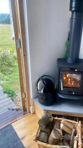 a fireplace in a room with a basket of rocks at Under the Stars Shepherds Huts at Harbors Lake in Newchurch