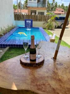 a bottle of wine and two wine glasses on a table at Casa Conchas do Patacho in Pôrto de Pedras