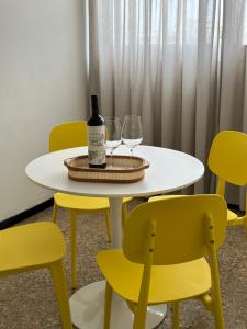 een witte tafel met twee wijnglazen en gele stoelen bij Avenida Colon Trendy APT in Mendoza