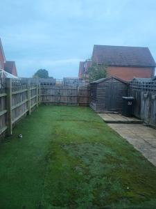 a backyard with a fence and a grass yard at The Haven Comfort in Harold Wood