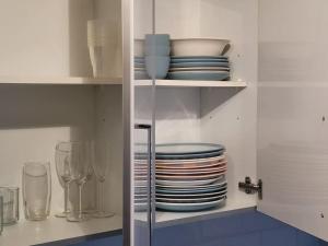 um armário branco com pratos, taças e copos em The Haven Comfort em Harold Wood