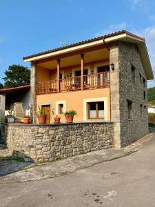 ein Haus mit einer Steinmauer und einem Balkon in der Unterkunft La Xana del Profundu in Villaviciosa