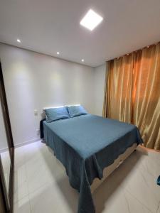 um quarto com uma cama com lençóis azuis e uma janela em Serra do cipó Casa do Fábio em Santana do Riacho