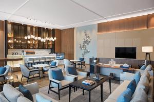 a living room with couches and chairs and a television at Courtyard by Marriott Shanghai Songjiang in Songjiang