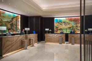 un vestíbulo con 3 personas de pie en el mostrador de recepción en Renaissance Suzhou Hotel en Suzhou