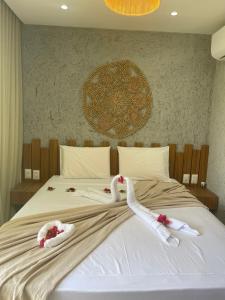 two swans are laying on a bed with towels at Nauru Chalés Milagres in São Miguel dos Milagres