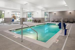 a swimming pool in a hotel with chairs and tables at SpringHill Suites by Marriott Kalamazoo Portage in Portage