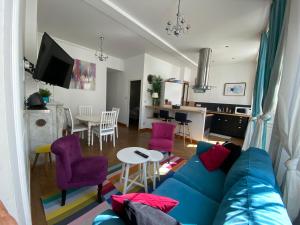 sala de estar y cocina con sofá azul y sillas moradas en SDCPM Maison de Maitre, en Conliège
