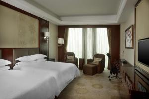 瀋陽市にあるシェラトン シェンヤン サウス シティ ホテルのベッド2台、薄型テレビが備わるホテルルームです。