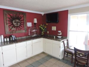 a kitchen with white cabinets and a red wall at Budget Inn Temple in Temple