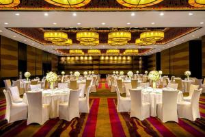 um salão de banquetes com mesas e cadeiras brancas e lustres em The Westin Beijing Chaoyang em Pequim