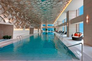 ein Pool in einem Hotel mit Stühlen und einem Gebäude in der Unterkunft Sheraton Grand Beijing Dongcheng Hotel in Peking