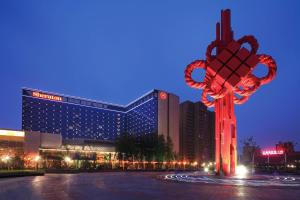 duży budynek z dużą czerwoną rzeźbą przed nim w obiekcie Sheraton Hefei Xinzhan Hotel w mieście Hefei