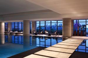 - une piscine dans un hôtel avec des chaises et des tables dans l'établissement Sheraton Hefei Xinzhan Hotel, à Hefei