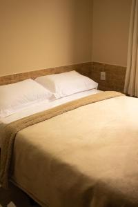 a large bed with white sheets and pillows at Chalé 31 in Florianópolis