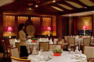 un restaurante con mesas y sillas blancas y una mujer en Courtyard By Marriott Shanghai Pudong en Shanghái