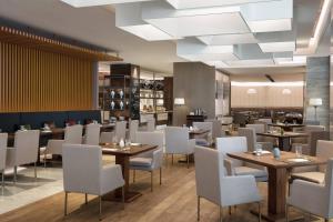 a restaurant with wooden tables and white chairs at Courtyard By Marriott Xi'an North in Xi'an