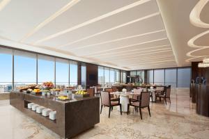 um restaurante com mesas e cadeiras e janelas grandes em The International Trade City, Yiwu - Marriott Executive Apartments em Yiwu