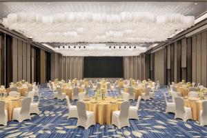 una grande sala da ballo con tavoli, sedie e un palco di Courtyard by Marriott Jiangsu Taizhou a Taizhou