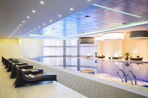 a swimming pool in a hotel with tables and chairs at Renaissance Shenyang West Hotel in Shenyang