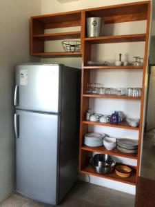 eine Küche mit einem Kühlschrank und Regalen mit Geschirr in der Unterkunft CasaCalypso Grenada in Belmont