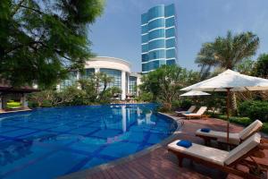 una piscina con sillas, una sombrilla y un edificio en Sheraton Fuzhou Hotel, en Fuzhou