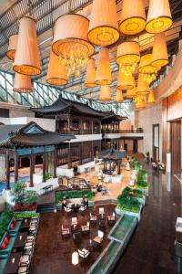 un gran vestíbulo con mesas, sillas y lámparas de araña en Sheraton Zhuhai Hotel en Zhuhai