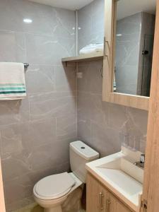 een badkamer met een toilet, een wastafel en een spiegel bij Apt in Bogotá Downtown in Bogota