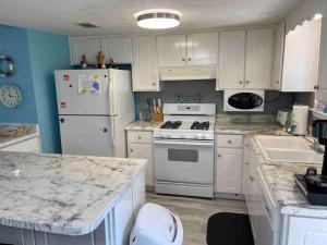 a kitchen with white appliances and white cabinets at Wanderlust Villa only 3 min walk to the Sand! in Panama City Beach