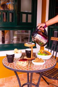 a person holding a tea kettle on a table with food at Chalé 31 in Florianópolis