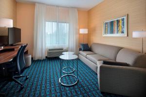 a living room with a couch and a desk in a hotel room at Fairfield Inn & Suites by Marriott Syracuse Carrier Circle in East Syracuse
