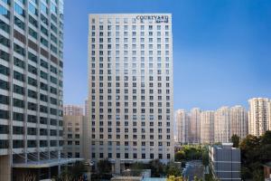 wysoki budynek z znakiem na górze w obiekcie Courtyard by Marriott Tianjin Hongqiao w mieście Tiencin