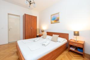 Schlafzimmer mit einem großen weißen Bett mit einem Kopfteil aus Holz in der Unterkunft Studio Duce 946b in Duće