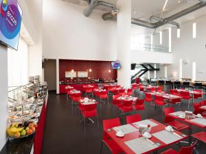 une salle à manger avec des tables rouges et des chaises rouges dans l'établissement Ramada Encore by Wyndham Aguascalientes, à Aguascalientes
