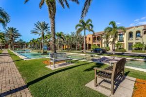 a park with benches and palm trees in front of a building at Yuba Oasis in Lely Resort