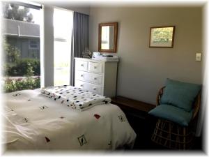 a bedroom with a bed and a chair and a window at Peaceful Pukerua Bay in Pukerua Bay