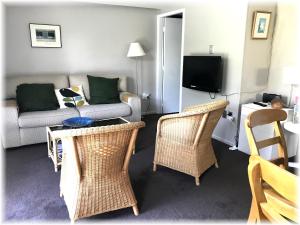 uma sala de estar com um sofá e cadeiras de vime em Peaceful Pukerua Bay em Pukerua Bay