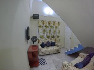 mit Blick auf ein Wohnzimmer mit einem Sofa und einem TV in der Unterkunft Sobrado Aconchegante - Praia Peruíbe in Peruíbe