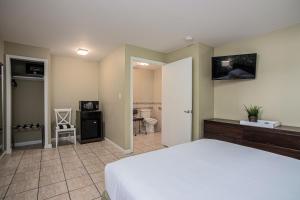 a bedroom with a white bed and a bathroom at The Local - St. Augustine in St. Augustine