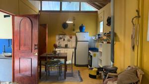 a small kitchen with a table and a refrigerator at CABAÑA JACARANDA in Horcon