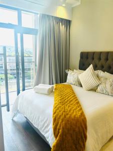 a bedroom with a bed with a yellow blanket on it at The Comfort AirB&B - Top floor luxury 1 bedroom apartment with views in Pretoria