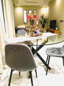 a dining room table with chairs and a vase of flowers at The Comfort AirB&B - Top floor luxury 1 bedroom apartment with views in Pretoria